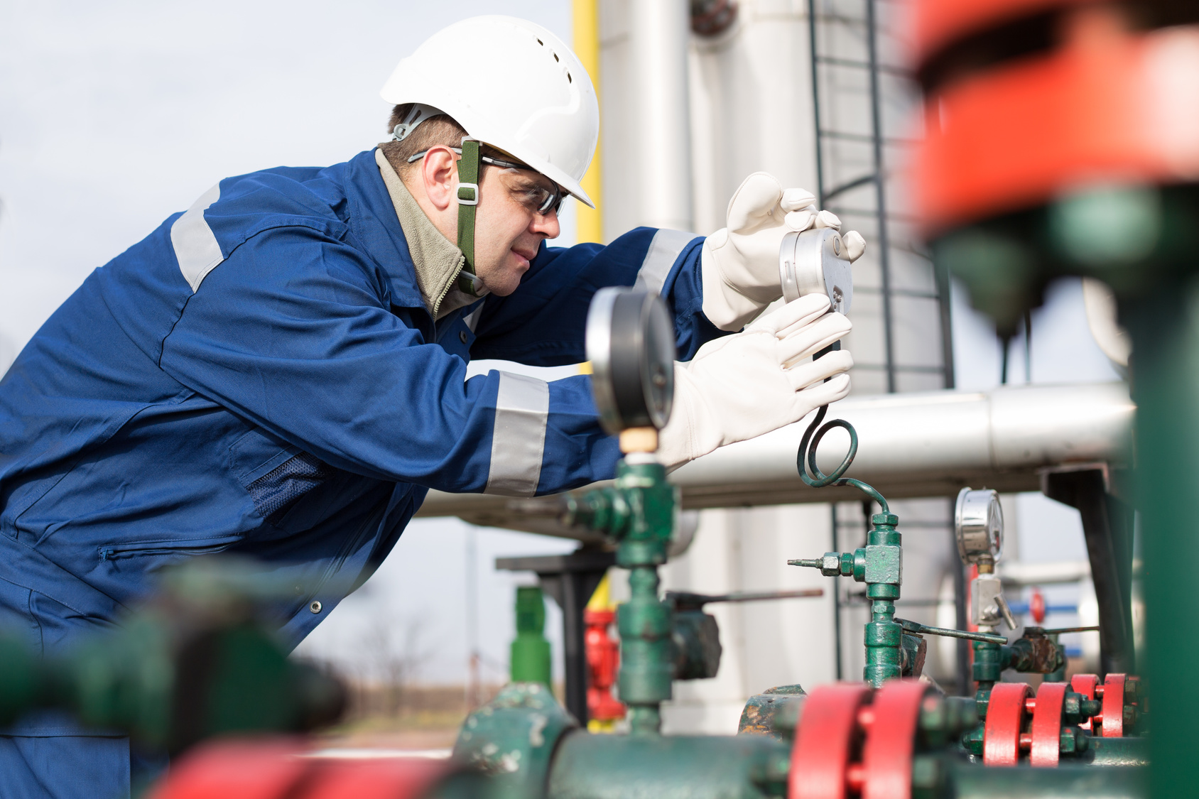 An industrial technician inspecting pipework and gauges